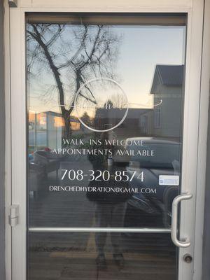 Drenched Hydration Beauty + Wellness door sign with appointment phone number